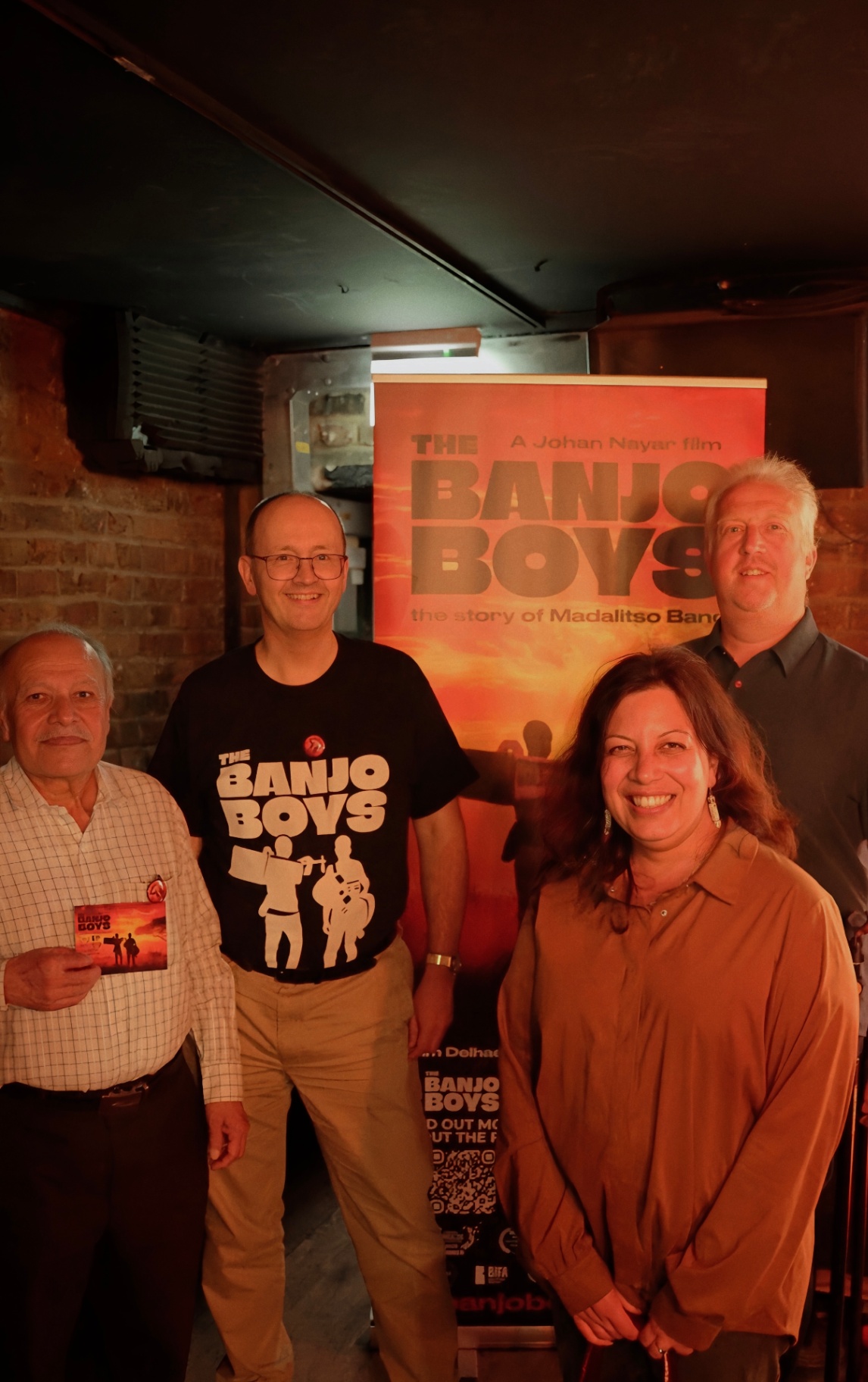 Mark Chandler and friends beside The Banjo Boys poster at The Madalitso Experience