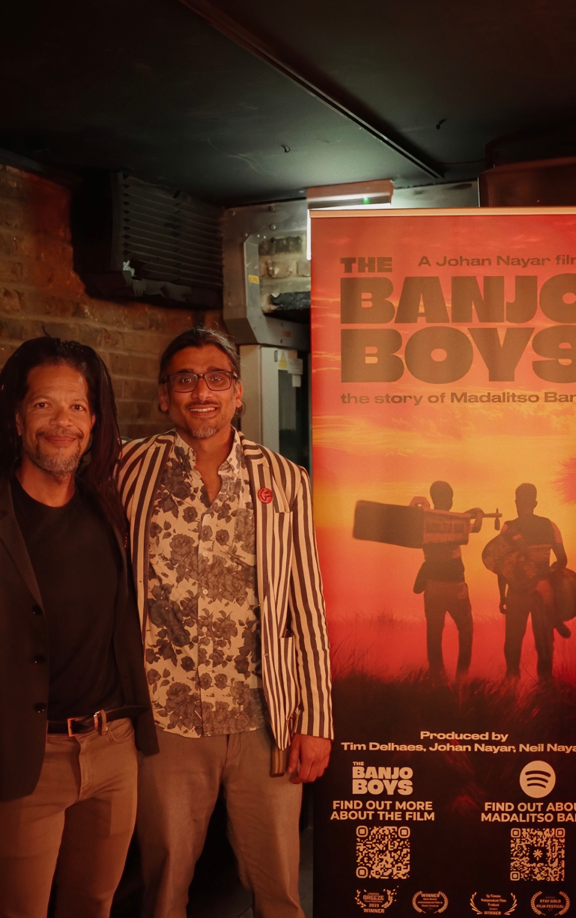 Johan Nayar with Ron Nkomba, a Malawian, beside the full Banjo Boys poster at The Madalitso Experience at the Troubadour, London