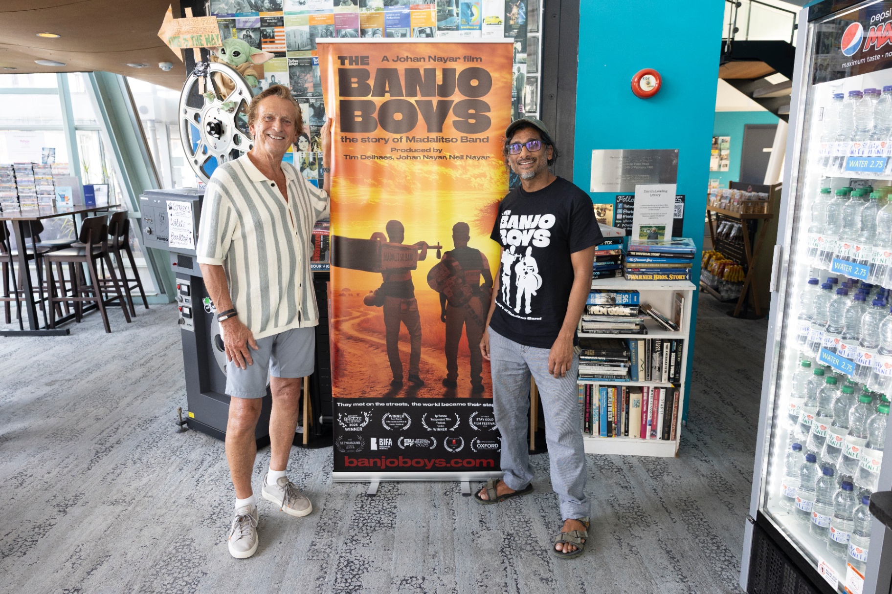 Johan Nayar with Roy Sutton, a fan of world music, beside The Banjo Boys poster at Harbour Lights, Southampton