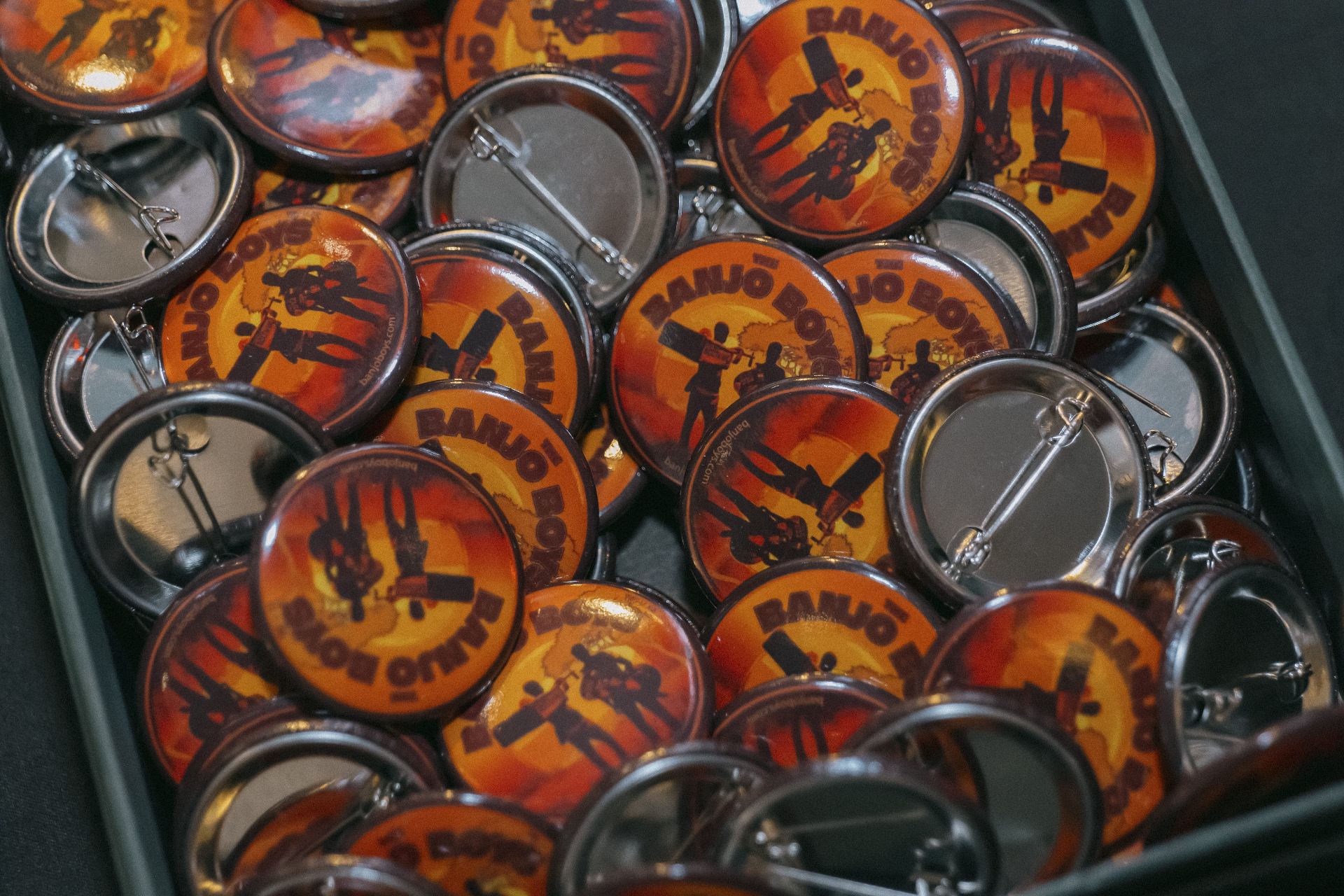 Tray of The Banjo Boys pin badges at the merchandise table in Bristol