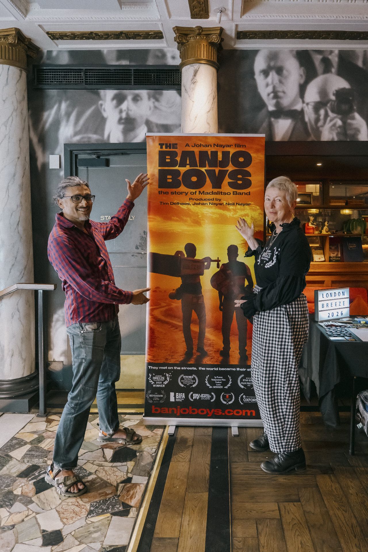 Johan Nayar and Madeleine Casey striking a pose beside The Banjo Boys banner in the Bristol cinema foyer