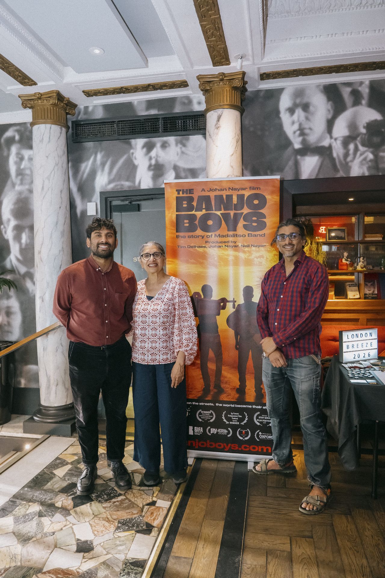 Producer, guest and director Johan Nayar posing beside The Banjo Boys banner in Bristol