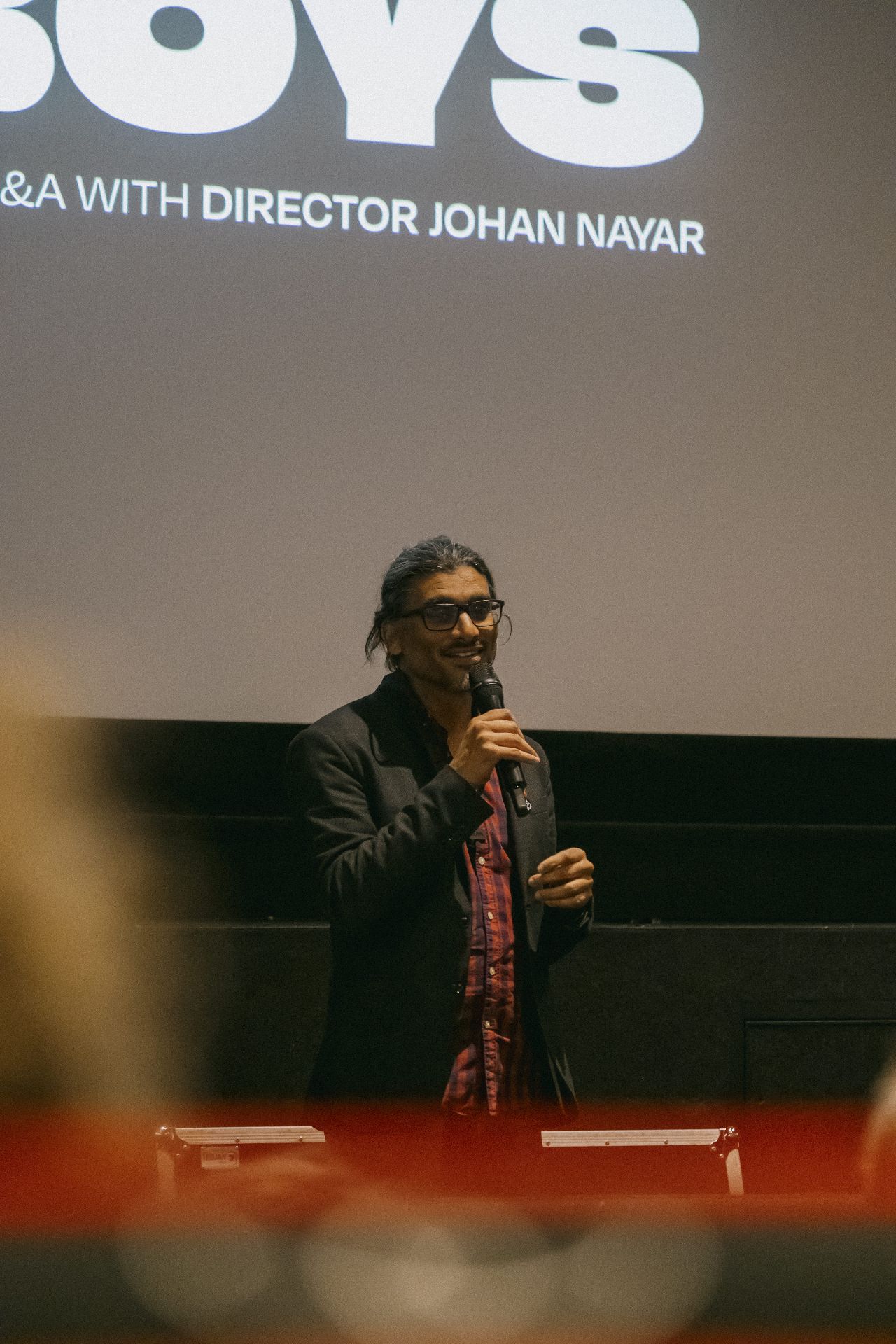Director Johan Nayar addressing the audience beneath The Banjo Boys title card at Everyman Bristol