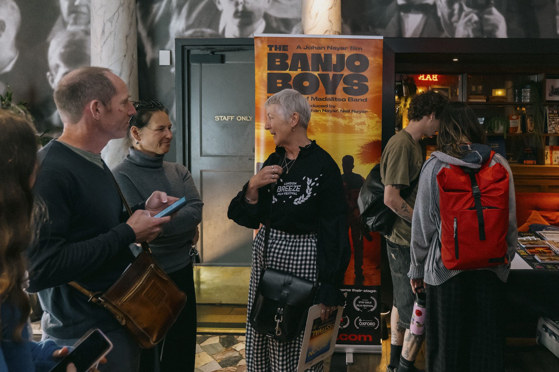 Guests in conversation in the cinema lobby beside The Banjo Boys banner in Bristol