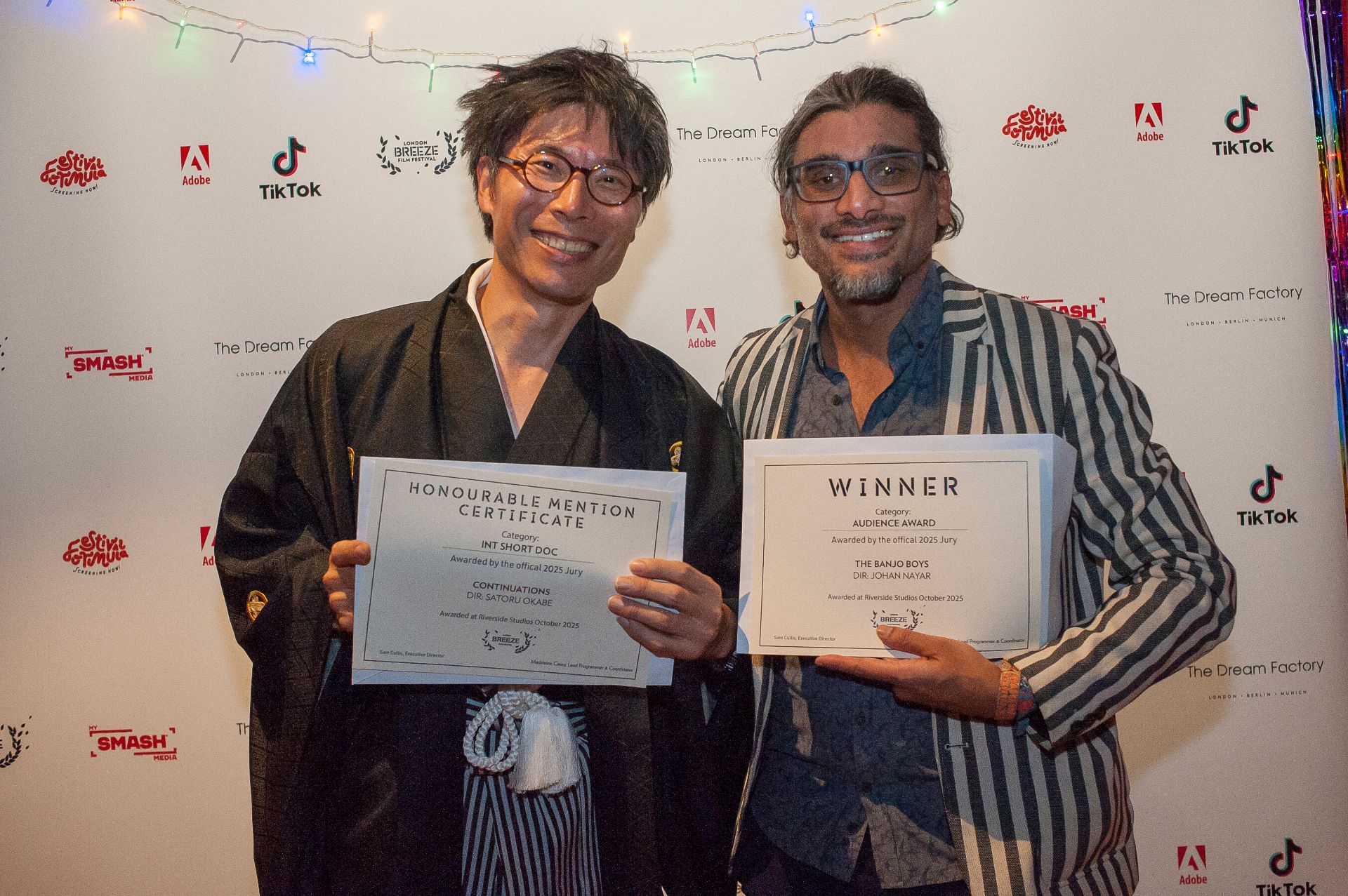 Johan Nayar with Audience Award certificate alongside Satoru Okabe with Honourable Mention at London Breeze Film Festival Awards Night — 26 Oct 2025